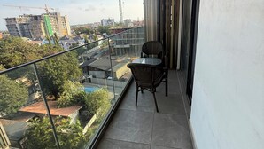 Een balkon met uitzicht op een bouwplaats, een stoel en een tafel.