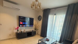 Een moderne woonkamer met een grote leren bank, een glazen salontafel, een flatscreen televisie en een kroonluchter.