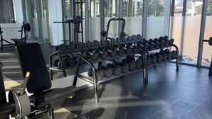 Een sportschool met trainingsapparatuur, grote ramen en een rubberen vloer.