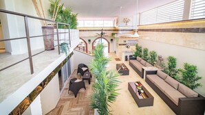 Un espacio interior amplio con techo alto, varias disposiciones de asientos y una diversidad de plantas en macetas.