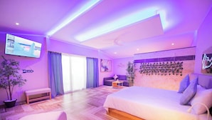 Una habitación de hotel moderna con una cama grande, un sofá, un televisor y un balcón.