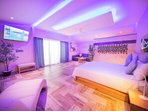 A modern hotel room with a large bed, a sofa, a TV, and a balcony. - Luxury 6 Bedroom Villa in Sosua Beachfront Bliss Awaits (Sosúa)