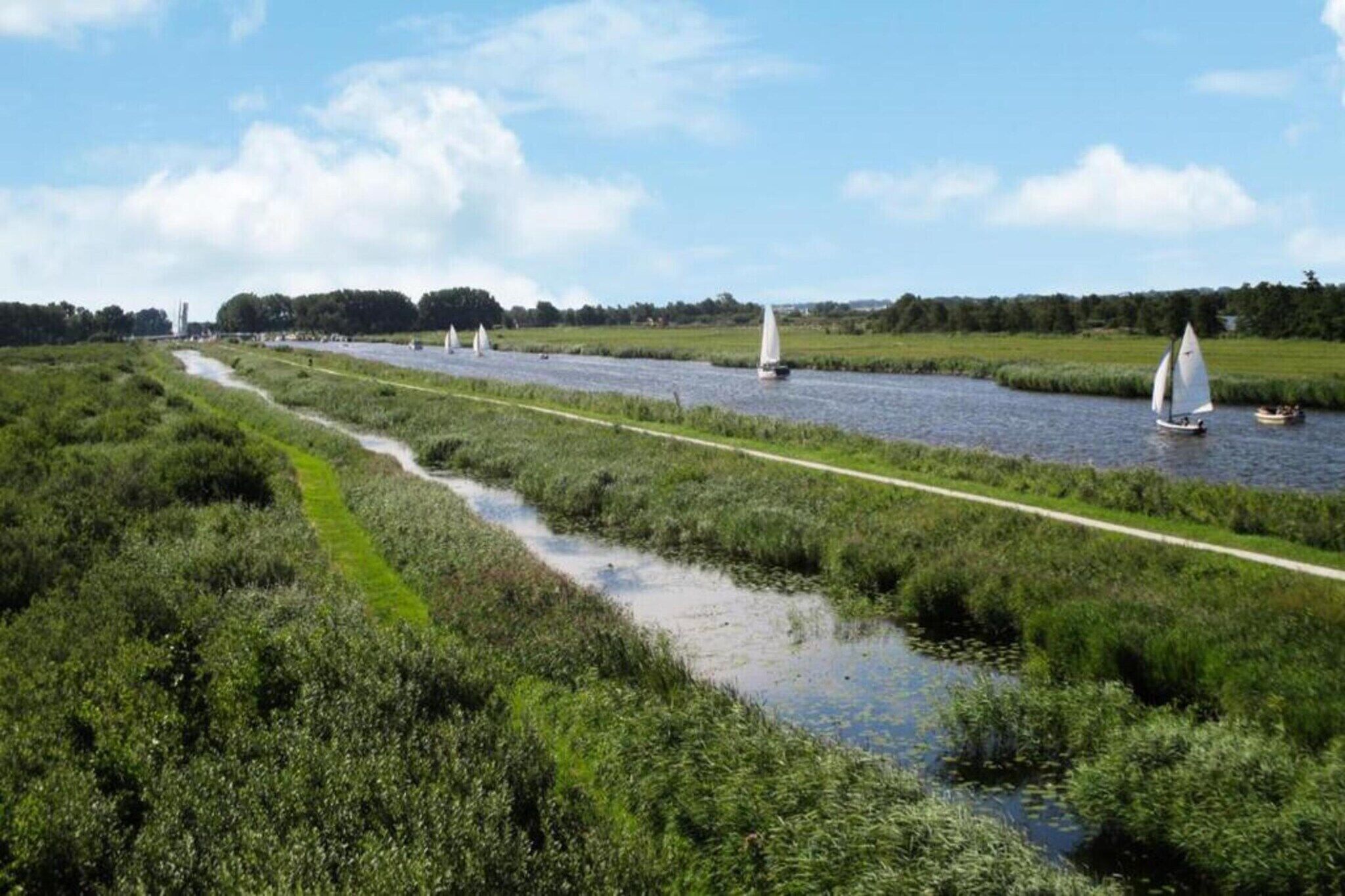 A riverside path with boats and greenery.