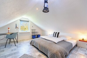 Ein Schlafzimmer mit Bett, Schreibtisch, Stuhl, Fenster und Deckenleuchte.
