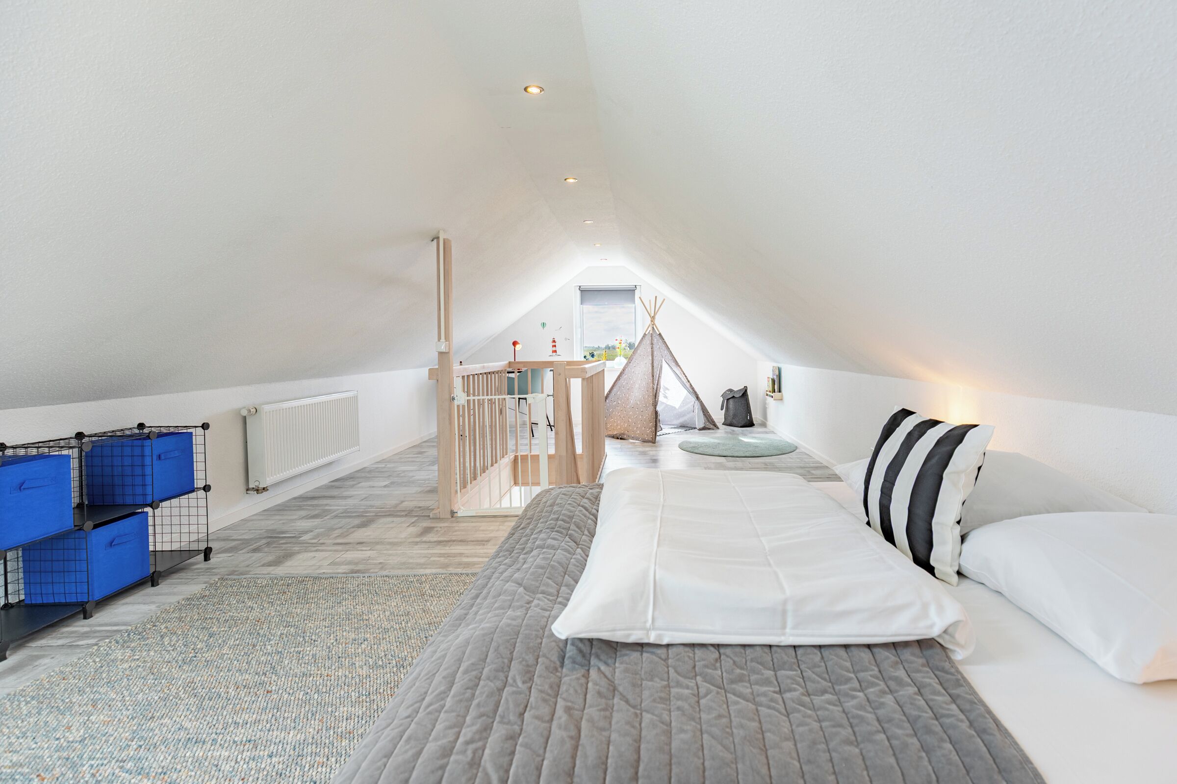 Ein Schlafzimmer mit Bett, Kissen, Stauraum, einem Fenster und Blick ins Freie.