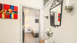 Ein Flur mit einem Bett, einem Spiegel und einer Vase mit Blumen auf einer Holzkonsole.
