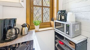 Eine kompakte Küche mit Kaffeemaschine, Mikrowelle und Backofen.