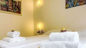 Ein Hotelzimmer mit einem Bett, zwei gerollten Handtüchern, einer Wandleuchte und einem Bild.