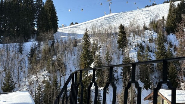 Ein schneebedeckter Berg mit einer Seilbahn und einem Gebäude im Hintergrund.