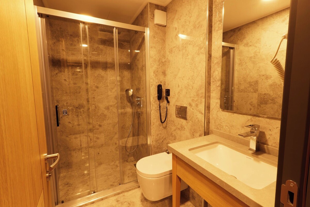 Un baño moderno con ducha acristalada, inodoro y lavabo con espejo.
