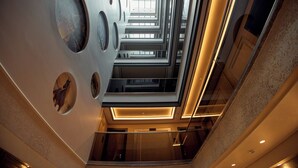 Ein modernes Interieur mit Glasdecke, geometrischen Wandmustern und einer zentralen Treppe.