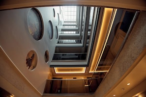 Un interior moderno con techo de vidrio, patrones geométricos en las paredes y una escalera central.