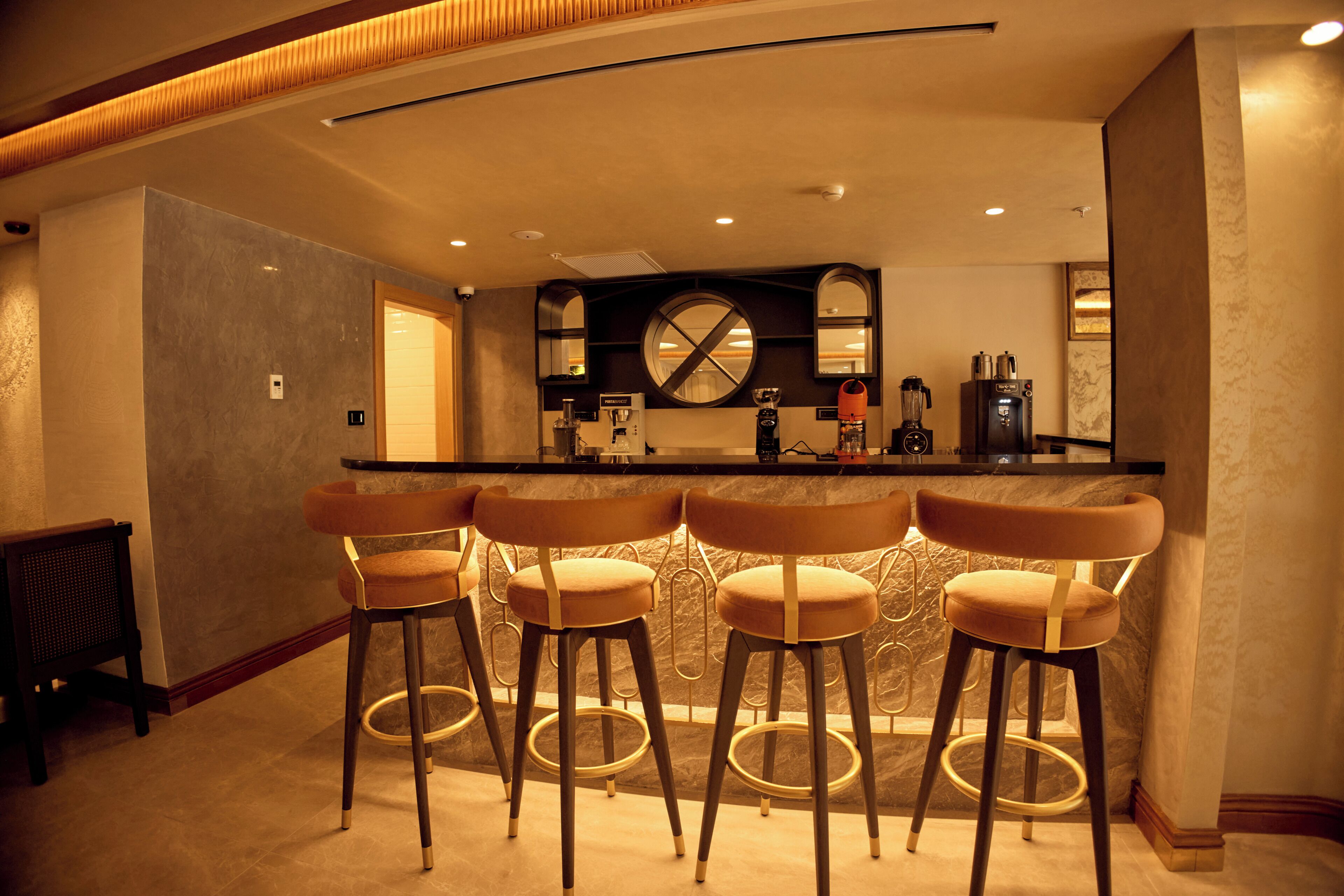 Un espace bar avec quatre tabourets, un comptoir et une machine à café.