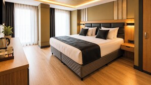Ein modernes Hotelzimmer mit einem großen Bett, Nachttischen, einer Kaffeestation und Blick auf die Stadt.