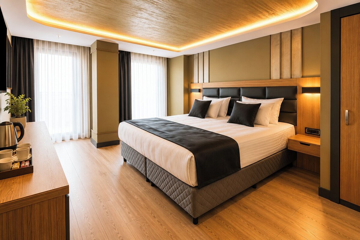 Una habitación de hotel moderna con una cama grande, mesitas de noche, un espacio para café y vistas a la ciudad.