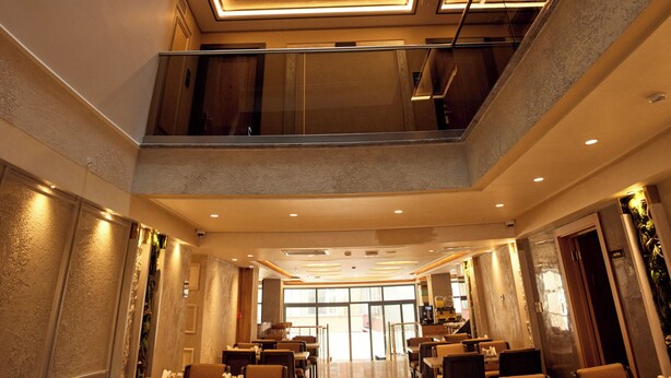 Ein modernes Hotelinnere mit einem zentralen Atrium, mehreren Restaurants und Blick zum Himmel durch die Decke.