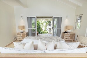 A bedroom with a bed, two nightstands, a window, and a view of greenery outside. - Beach Happy Schooner Bay 109 - by ZenBreak (Speightstown)