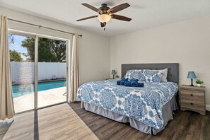 A bedroom with a bed, a ceiling fan, a nightstand, and a view of a swimming pool through a sliding glass door. - Siesta Key Pool BBQ Mini Putt 3BR 2BA Sleep 12 (Palmetto)