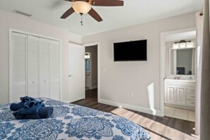 A bedroom with a bed, a ceiling fan, a TV, a closet, and a bathroom with a mirror and sink. - Siesta Key Pool BBQ Mini Putt 3BR 2BA Sleep 12 (Palmetto)