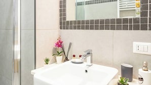 Un bagno con lavandino bianco, specchio e pareti rivestite di piastrelle.