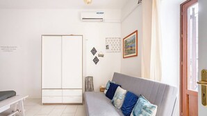 Una stanza con un divano grigio, un armadio bianco, un tavolino e una porta con maniglia in ottone.