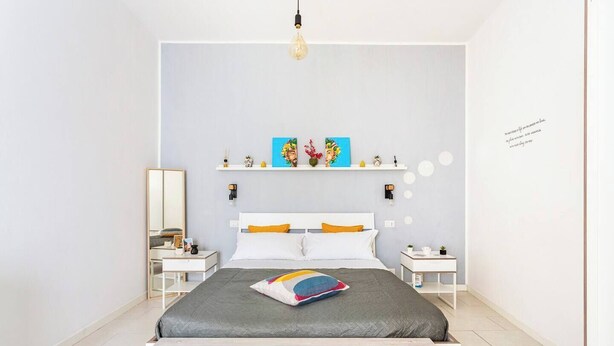 Una camera da letto moderna con un letto, comodini, uno specchio e decorazioni a parete.