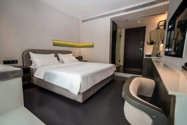 A modern hotel room with a large bed, bedside tables, a desk, and a mirror. - Laizhu Xingchen Hotel (Chengdu)