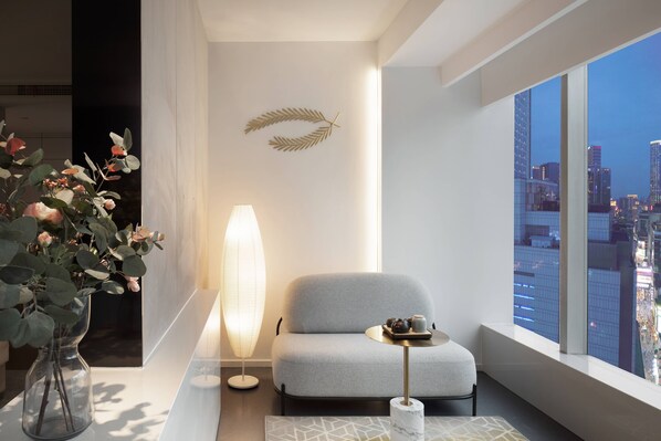 A modern room with a city view, a sofa, a table with a tray, a vase with flowers, and a tall floor lamp. - Laizhu Xingchen Hotel  (Chengdu)