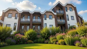 A multi-story residential building with balconies, surrounded by a well-maintained garden with various flowering plants. - 4 Person Holiday Park Home in Dienstweiler (Oberhambach)