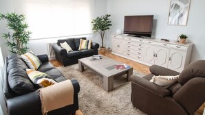Un salon comprenant un canapé, une table basse, un téléviseur et un meuble.