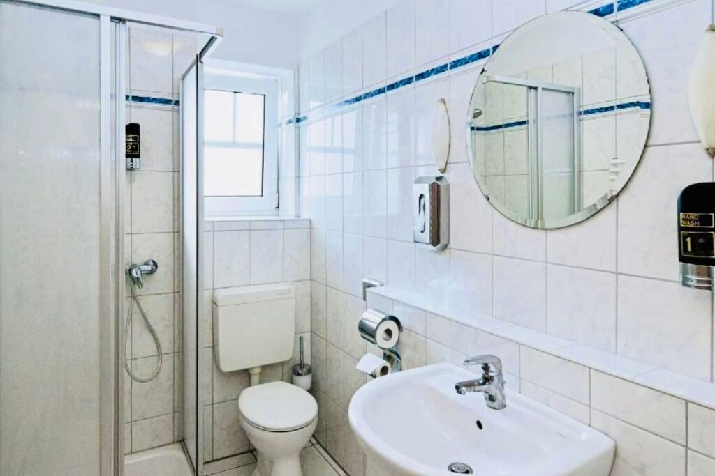 A bathroom with a shower, toilet, sink, and a mirror.