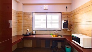 Una cocina compacta con ventana, un lavamanos, un hervidor, un microondas y un dispensador de agua.