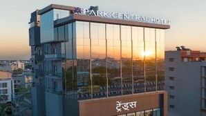 Ein modernes Hotel mit Glasfassade, einer Beschilderung mit dem Schriftzug 'Park Central Hotel' und einem Geschäft im Erdgeschoss.