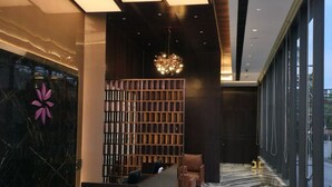 Eine moderne Lobby mit einer Rezeption, einer Sitzecke und einer Wand mit geometrischem Muster.