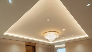 Ein modernes Interieur mit einem geometrischen Deckenmuster, eingelassener Beleuchtung und einem zentralen Kronleuchter.