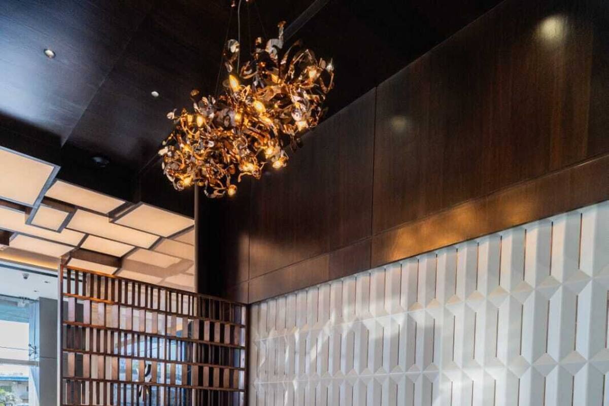 A modern lobby with a leather sofa, a wooden bookshelf, and a patterned wall.
