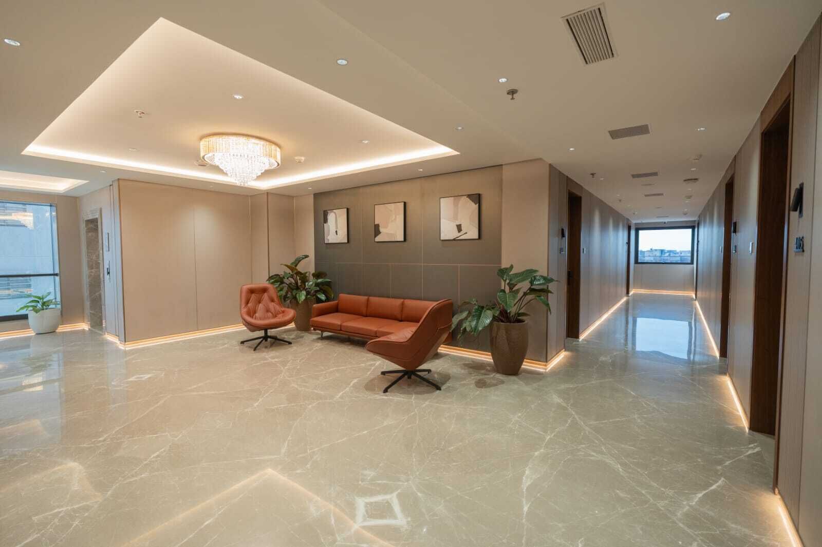 Un hall d’entrée moderne avec un sol en marbre, un canapé, un fauteuil et un lustre.