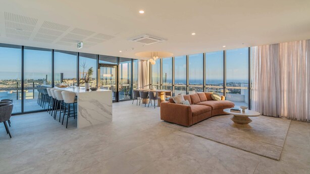 A modern living room with a sofa, a coffee table, and a dining area with chairs and a table. - Elevated 3BR Stay - Views, Amenities, Parking (Newcastle West)