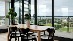 A modern dining area with a large table, chairs, and potted plants. - Elevated 3BR Stay - Views, Amenities, Parking (Newcastle West)