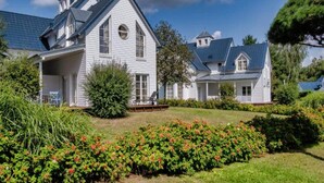 A large white house with a blue roof, surrounded by a well-maintained garden and a clear blue sky. - 4 Person Holiday Park Home in Glindow (Werder (Havel))
