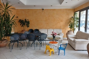 A room with a dining area, sofa, and chairs, featuring a large window and potted plants. - RG003 - Bellaria, comfortable apartment 100 meters from the sea (Bellaria)