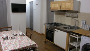 Une cuisine compacte comprenant une table à manger, une cuisinière, un four et un lave-linge.
