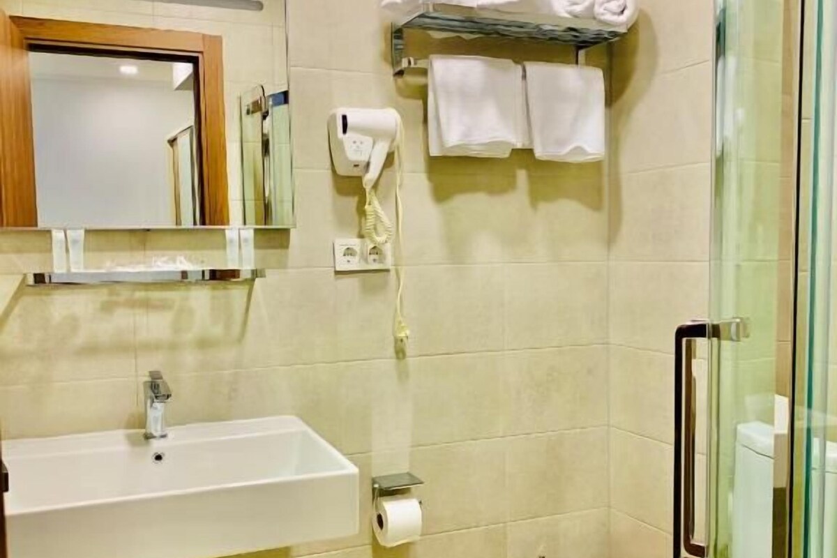 A bathroom with a sink, mirror, towel rack, toilet, and glass shower enclosure.
