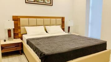 A hotel room with a bed, two bedside tables, a nightstand, a lamp, and a window.