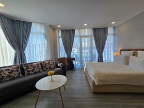 A hotel room with a bed, sofa, round table, and curtains. - Tsereteli Palace (Batumi)