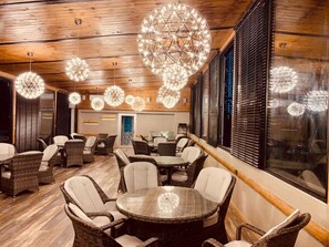 A room with wicker furniture, a round table, and decorative spherical light fixtures. - Tsereteli Palace (Batumi)