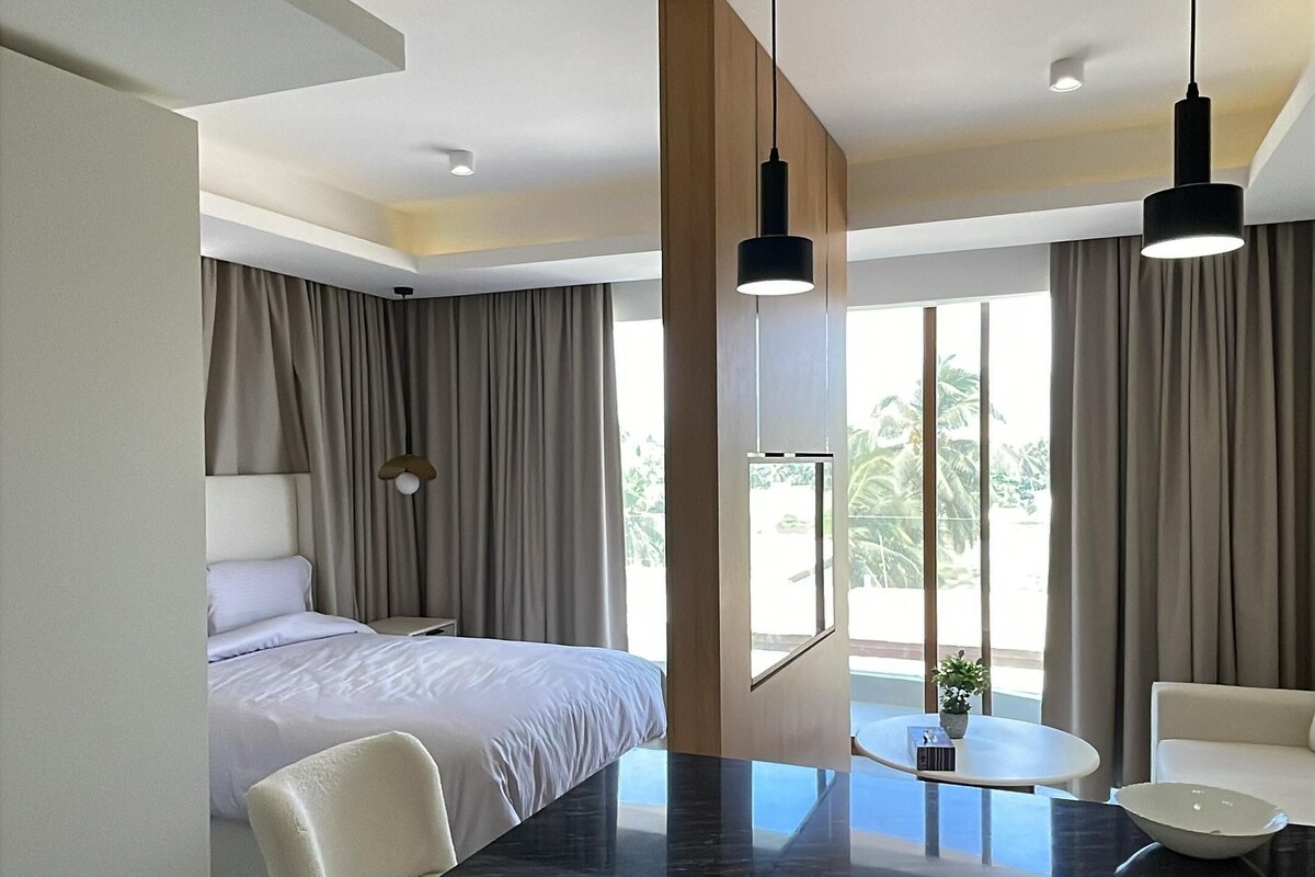 Een moderne hotelkamer met een bed, een bureau met een wasmachine, een stoel en uitzicht op het omliggende landschap.