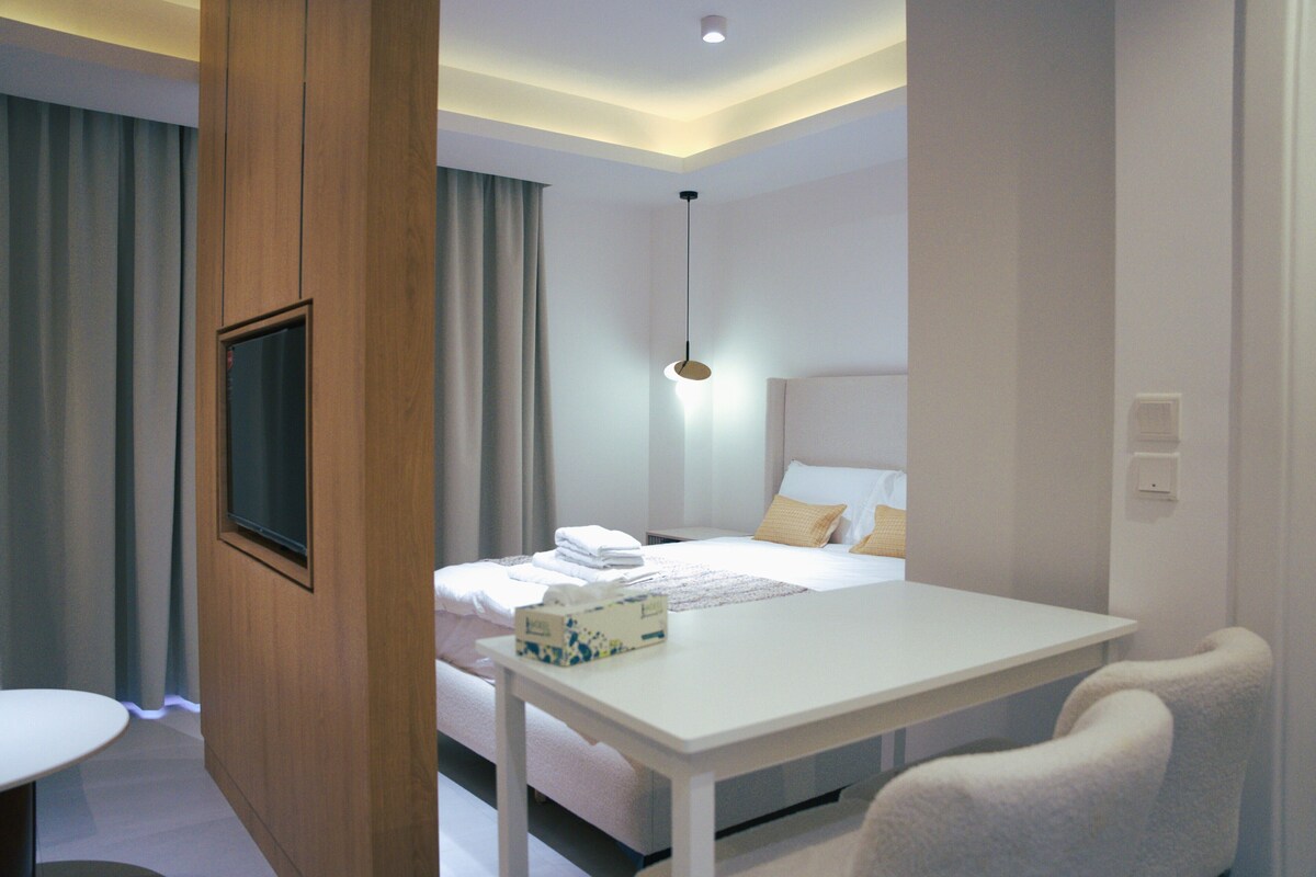 Een hotelkamer met een bed, nachtkastje en een aan de muur bevestigde televisie.
