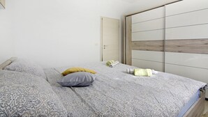 Een slaapkamer met een bed, kussens, een nachtkastje en een kledingkast.