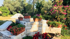 A stone-built garden with flower beds and potted plants. - Charming vacation home with garden (Umag)